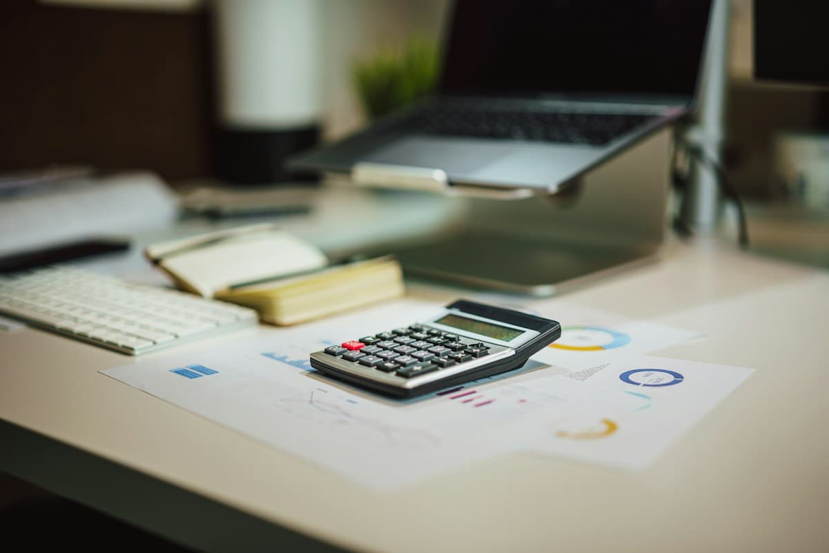 Calculator on printed reports beside a laptop